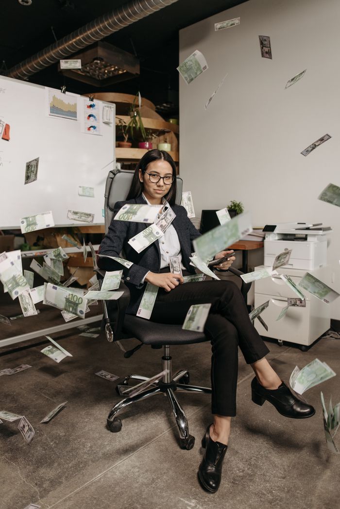 services-04 Businesswoman in modern office with falling cash, symbolizing financial success.